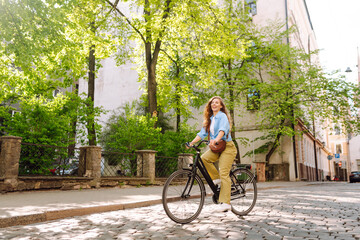 Beautiful woman riding bicycle at the city street outdoor. Active lifestyle. Eco transport.