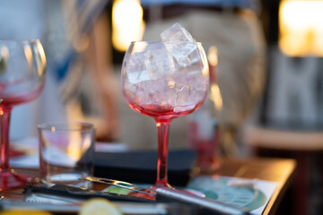 the bartender prepares an alcoholic cocktail by pouring ice cubes into a glass