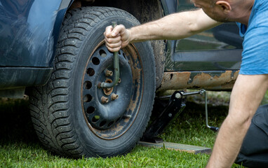A skilled man meticulously working on a tire of a rugged truck, his hands expertly maneuvering...