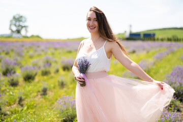 beautiful girl in a dress on a lavender field with a bouquet of flowers