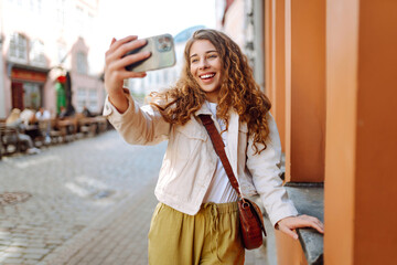Lifestyle selfie portrait of young positive woman having fun and taking selfie in city center....
