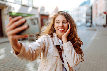 Lifestyle selfie portrait of young positive woman having fun and taking selfie in city center....