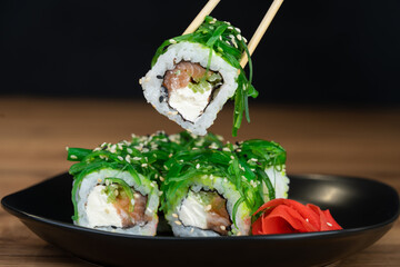 delicious traditional Japanese sushi and rolls on a plate holding chopsticks
