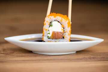 delicious traditional Japanese sushi and rolls on a plate holding chopsticks