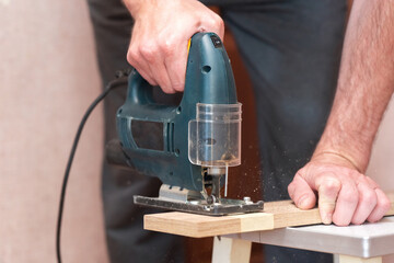A worker cuts a board with a jigsaw