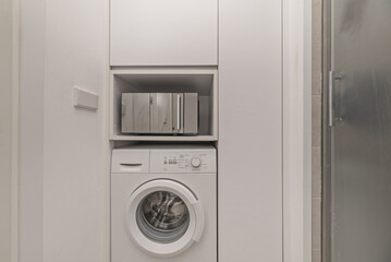 A white wooden cabinet with a built-in washing machine and microwave