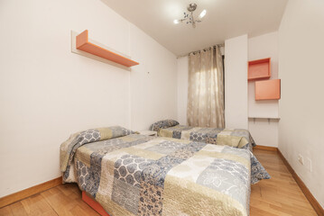Bedroom with two single beds, white painted walls, light wooden shelves and curtain with white circle pattern