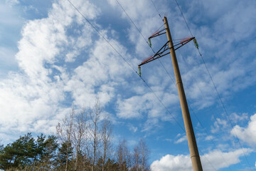 Power lines and high-voltage wires against a background of blue sky and fluffy clouds. Energy...