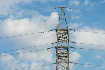 Obraz premium Power lines and high-voltage wires against a background of blue sky and fluffy clouds. Energy infrastructure of Ukraine.