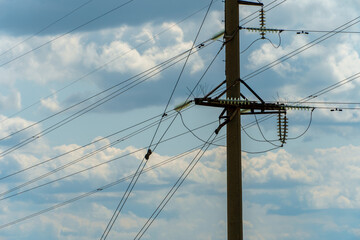 Power lines and high-voltage wires against a background of blue sky and fluffy clouds. Energy...