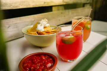 Cocktails with nachos with cream and spicy tomato pepper sauce at beach bar in summer