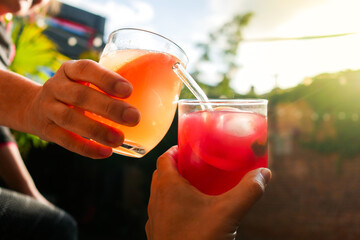 Friends drinking cocktails in evening sunlight in summer 