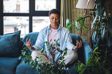 Young African American woman in casual clothing doing home meditation. Relaxation, mental health,...