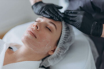 portrait of a young attractive woman getting facial massage with cream. 