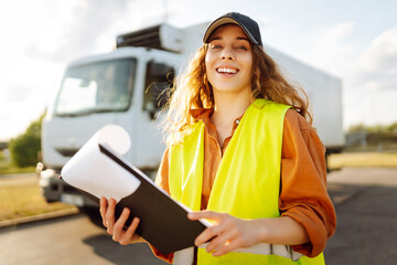 Portrait of a female trucker standing in front of truck and looking at camera.Transportation services. Logistic shipping.