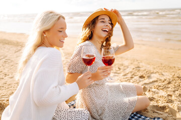 Two women female friends having picnic brunch with wine, sitting near sea. Vacation , relax,...