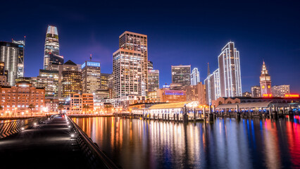 Twilight cityscape with glowing skyscrapers and water reflections