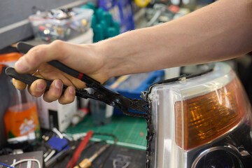 showing hands effectively repairing a car headlight in a workshop environment