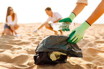 Trash on the beach. Volunteers activists collects garbage cleaning of beach coastal zone. Woman...
