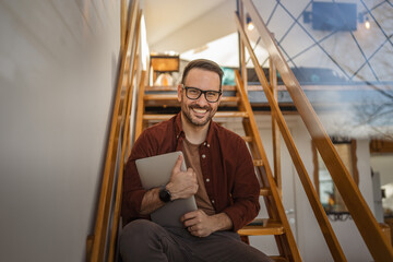 Portrait of adult man sit and laptop on the stairs at home