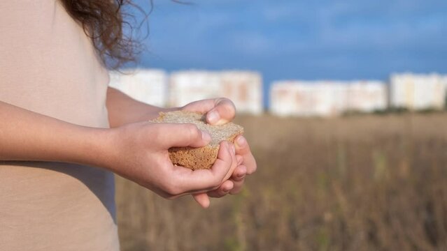 Hungry child hands with bread by field. a hungry child stand in the fild with bread to eat during crisis time.