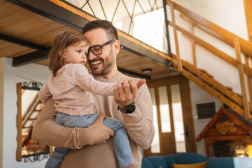 Adult caucasian man father hold his daughter and hug her at home