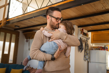 Adult caucasian man father hold his daughter and hug her at home
