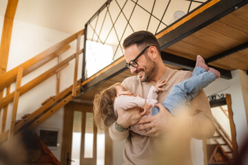 Adult caucasian man father hold his daughter and hug her at home