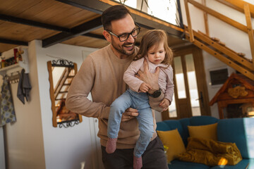 Adult caucasian man father hold his daughter and hug her at home