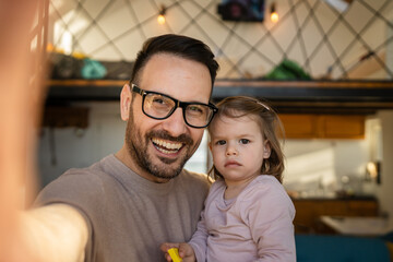 Adult father man hold his daughter toddler and take a self portrait