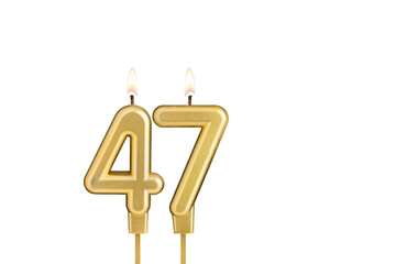 Golden number 47 birthday candle on white background