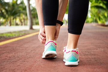 Runner woman tying up laces of shoes, getting ready to run for cardio and weight loss