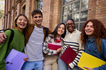 Portrait of a cheerful group of young multiracial student looking at camera having fun outside at...
