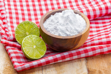 Baking soda in wooden bowl and lemons, on the table