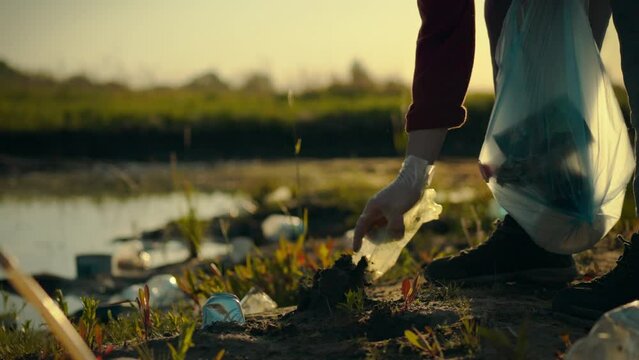 Concerned about the environment, the young man actively collects garbage and plastic waste, sorting it into bags for further recycling. He cleans the coastal area, clearing it of debris
