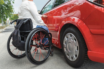 Female driver with disability entering a car, a wheelchair user on the way to work. Concepts of...