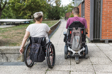 Two friends with disability, wheelchair users traveling down the city street. Accessibility for...