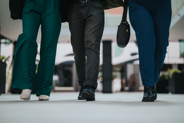 Three business professionals walking side by side outside a contemporary office building. Teamwork...