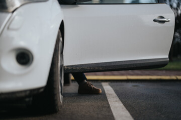 A focused shot showing a white vehicle's side door covered in dirt next to asphalt, with...