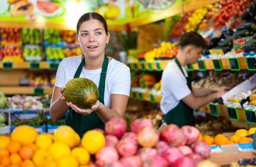 Friendly female vendor laying out ripe melon on the counter