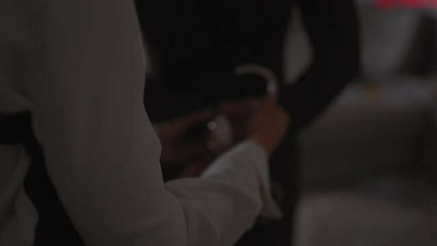 Handcuffed woman in dimly lit room with plainclothes officer, depicting arrest or investigation.