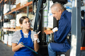 Mature man drive operate automatic fork lift loader and answers young female auditors questions....