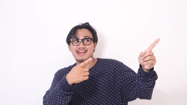 Footage of adult Asian man smiling happily and pointing both hands to the side.