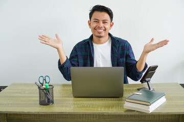 young asian businessman sitting at workplace having doubts with both arms open to the sides