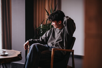 A cozy scene featuring a young man smiling and relaxing in a chair at home, with a warm and welcoming atmosphere.