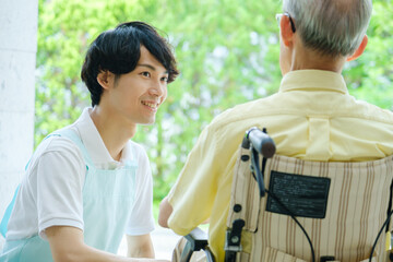 車椅子に乗った高齢者と会話をする介護福祉士