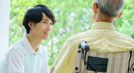 車椅子に乗った高齢者と会話をする介護福祉士