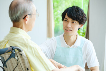 車椅子に乗った高齢者と会話をする介護福祉士