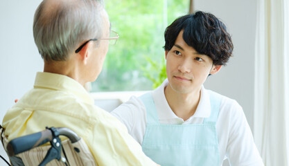 車椅子に乗った高齢者と会話をする介護福祉士