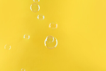 Beautiful transparent soap bubbles on yellow background, space for text